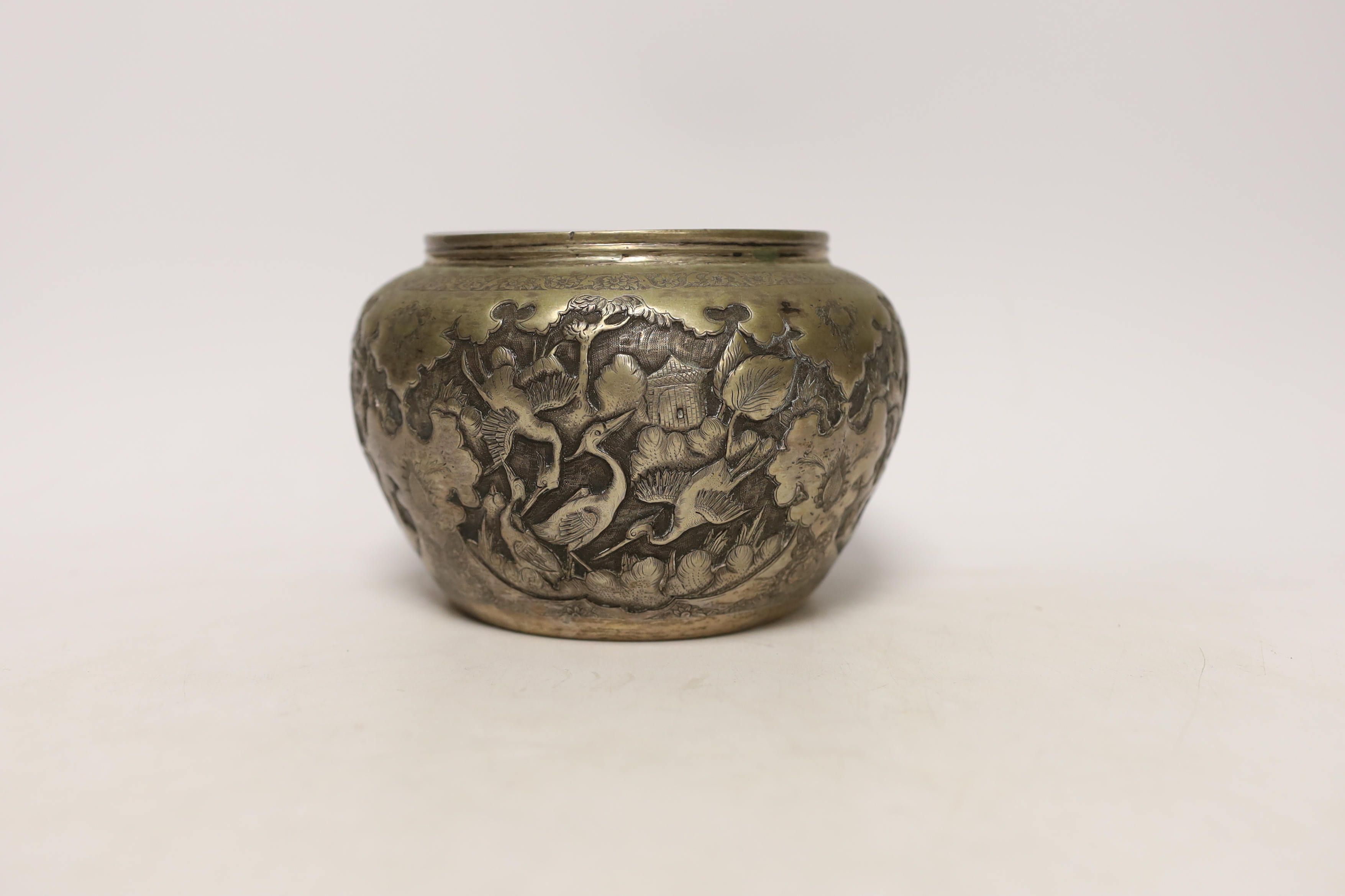 A Persian white metal bowl decorated in relief with animals and flowers, indistinct marks to the base, 16cm wide
